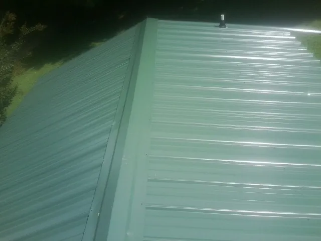 New green metal panels meeting at the ridge of a roof — Flat Roof Repair work by our crew in Upland