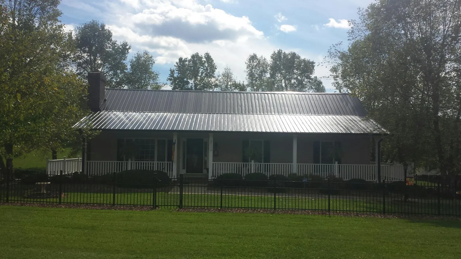 Gray metal roof on a brick ranch with a full width front porch — Gutter Guard Installation work by our crew in Upland