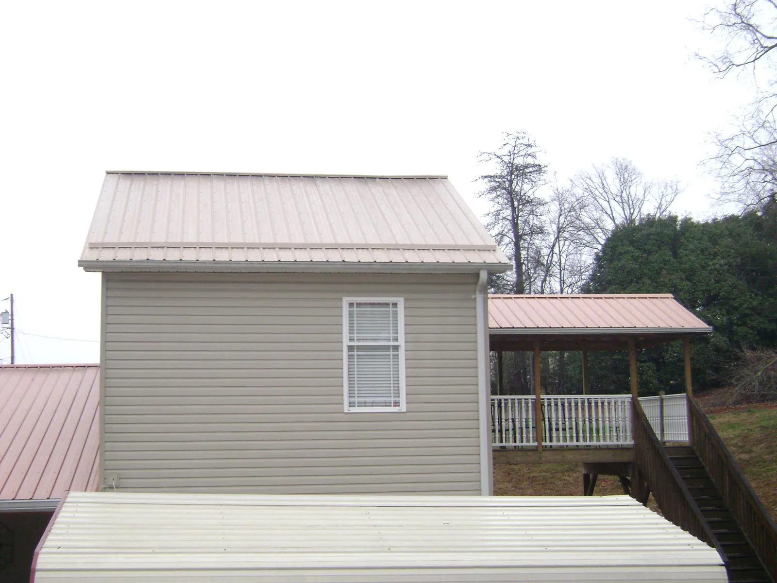 Tan metal roofs on a two story addition and attached porch, from a Roof Replacement job in Upland